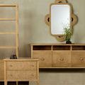 Mirrored wall scene with the rectangle rattan mirror above wooden sideboard and matching light furniture