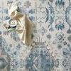 Top view close-up of rug’s central medallions with textured printed design and beige throw on top