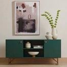 Lira Bowl displayed inside dark green cabinet shelf under abstract artwork in a room setting