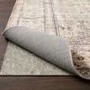 Side angle showing beige rug pad underneath a patterned rug corner on hardwood floor