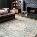 Rosette Denim Fog rug in a dark, cozy living room setting with black brick fireplace and modern gray sofa