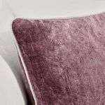 Close-up angled view of pillow on sofa showing subtle velvet sheen and piping