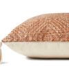 side view showing pillow’s textured orange front and plain cream back with tassel detail