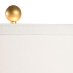 Close-up detail of the antique brass finial ball on top of the white drum shade