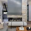 Living room setting with the Basis Taupe Rug under a wooden coffee table, by a modern metal and stone fireplace
