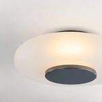 Flush mount light turned on, showing warm light glowing through the etched glass shade from below