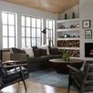 Living room scene with Ryan Drum Coffee Table, black leather chairs, blue area rug, and white built-in shelves