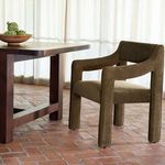 Elise Dining Chair next to wooden dining table on terracotta tiled floor in softly lit room
