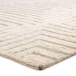 Close-up of thick high-low wool pile and detailed taupe geometric lines on cream background
