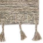 Detailed close-up of tassels and textured geometric trellis pattern in light taupe and cream yarns