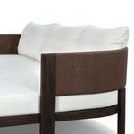 Close-up on curved armrest area with brown linear woven cording and white back cushions
