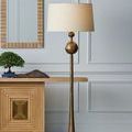 Repeat of antique brass floor lamp styled beside wood console and wall mirror in neutral room