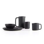 Black ceramic mug with handle shown alongside a pitcher, bowl, and plate on white background