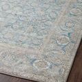 Angled close-up of rug edge highlighting curved border design and muted blue-beige tones