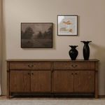 Citrine framed painting displayed on beige wall above wooden sideboard with black vases and adjacent monochrome art