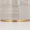 Detail of lamp base bottom with gold metal trim beneath the patterned white and black ceramic