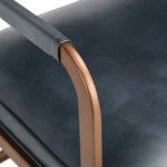 Close-up on bronze armrest wrapped in leather against dark leather seat cushion