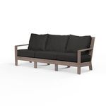 Laguna Sofa with hand-brushed aluminum frame mimicking driftwood, featuring plank arms and curved slat back with black cus...