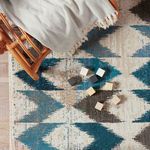 Overhead view of rug corner with wooden toy blocks scattered on blue-beige chevron pattern