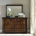 Leesburg Landscape Mirror shown mounted on dark wood dresser in a neutral room with decorative items on dresser