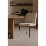 Danny Dining Chair placed in light-toned modern dining room with wood table and shelves