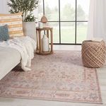 Rug styled in living room with beige sofa, side table, pouf, and large window background