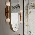 Close angle on sconce beside mirror showing textured art glass globes and subtle brass hardware