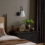 Wilma Sconce mounted above dark wood nightstand in bedroom setting with decor
