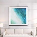 Bird's eye coastal print hanging above cream sofa with side lamps in white wall room