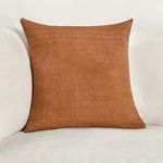 Brown basket weave pillow styled on light beige fabric sofa for scale and context