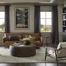 Living room setting with Kimmery Chair positioned beside leather sofa and round coffee table