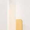 Close-up of matte cloud glass tube and smooth brushed brass backplate with visible texture on wall