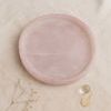Top view of pink alabaster tray on fabric with subtle matte surface and two small decorative accents