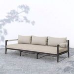 Sherwood sofa shown outdoors on stone patio with shadows and greenery nearby