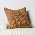 Pillow angled on white sofa highlighting knit front and smooth fabric back