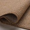 Curled edge close-up showing the flexible polypropylene material and woven texture of rug