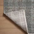 Close-up of rug corner flipped over revealing the reverse side’s plaid design and binding