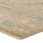 Close-up of rug corner showing the woven texture and fringed edge in neutral khaki and slate hues.