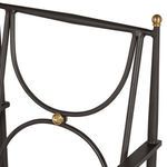 Close-up of chair back featuring curved wrought aluminum design and gold accent knob