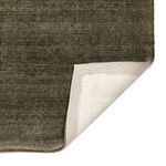 Folded corner revealing the white backing and green face side of Blanton Outdoor Rug