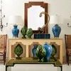 Console table styled in living room with mirror, blue lamps, artichoke decor, and side chairs