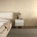 Nightstand styling in a bedroom with beige walls and decorative vase on top