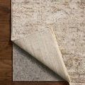 Rug corner lifted to reveal underside woven backing and padding beneath on hardwood floor