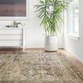 rug laid on light wood floor near large green potted plant and white dresser