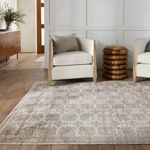 Rug in living area beneath two cream armchairs and a round wicker side table