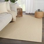 Beige solid rug styled in room with light gray sofa, woven ottoman, and wooden floor