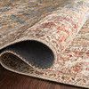 Rolled edge of rug revealing textured underside and tightly stitched binding in rust and blue