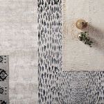 Various global rugs including Kimball Animal beige and bronze rug layered together with decorative objects