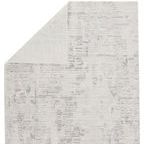 Back side of rug partially folded showing weave and neutral backing in ivory