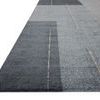 Low angle side view showing flat pile texture and edge of geometric pattern in slate and natural tones